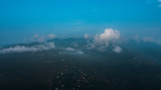 Clouds over the mountains with green trees