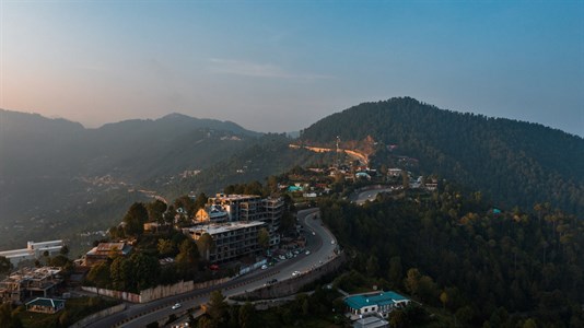 Aerial view of beautiful homes in green hills surrounded by trees in Murree, Pakistan