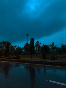 Rainy Road at night with clouds and trees in the background