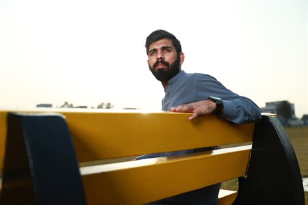 Young man looking back at something while seated on bench