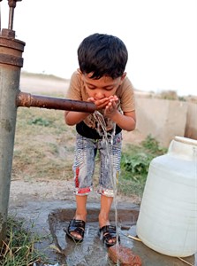 Baby drinking water through hand pump